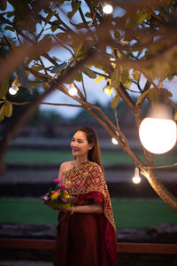 Portrait of young woman standing against plants