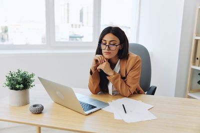 Portrait of young woman using laptop at office