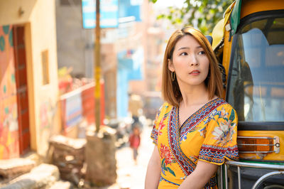 Beautiful woman looking away while standing by jinrikisha