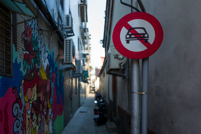 Road sign in alley amidst buildings in city