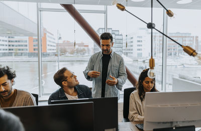 Businessmen discussing strategy amidst colleagues working at office