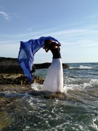 Woman standing at beach against blue sky