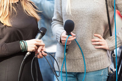 Midsection of journalists holding microphones