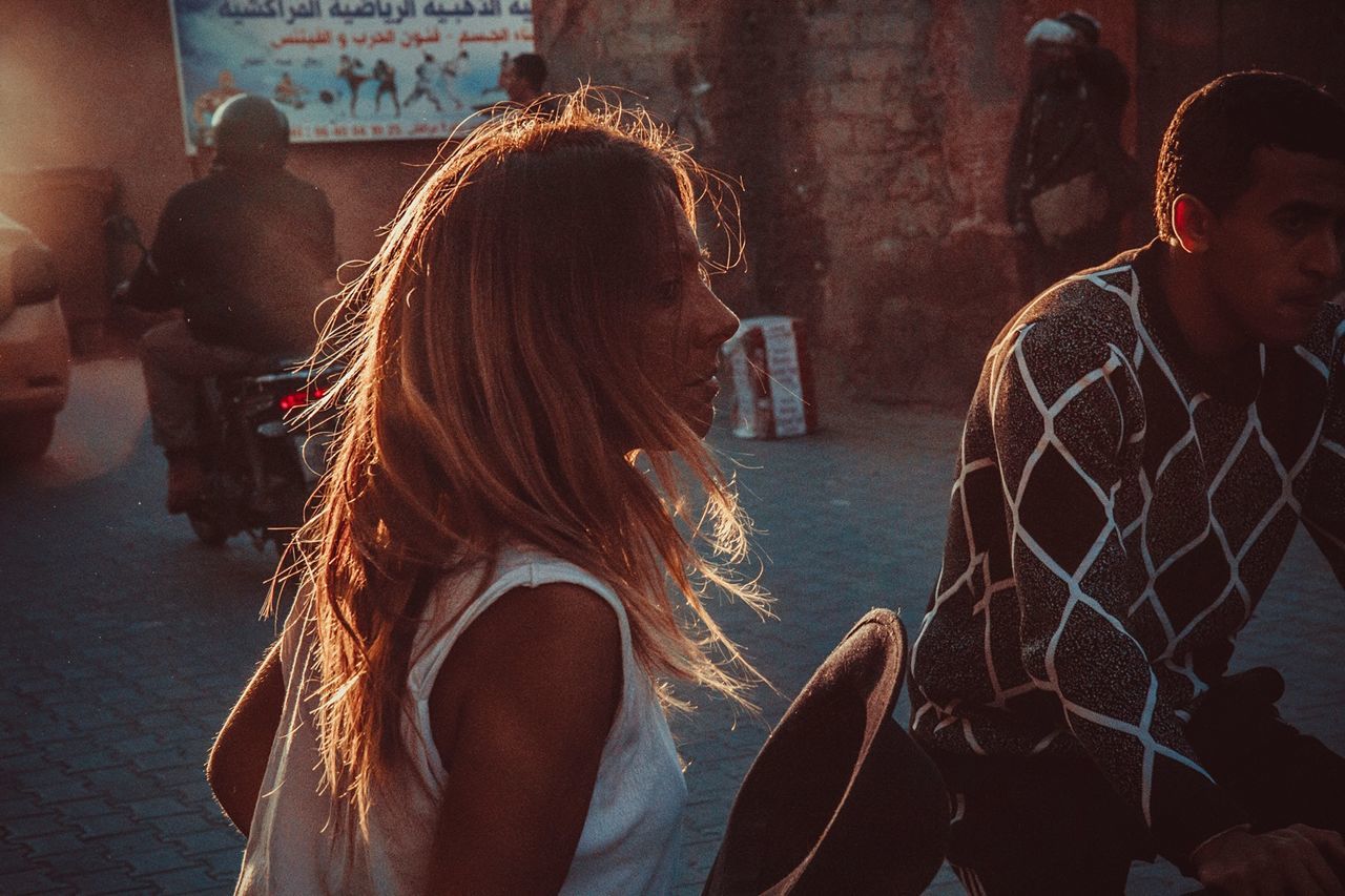 leisure activity, real people, incidental people, group of people, lifestyles, women, adult, young adult, hairstyle, togetherness, people, young women, long hair, city, architecture, sitting, hair, focus on foreground, street