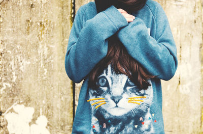 Midsection of woman wearing cat printed t-shirt while standing against wall