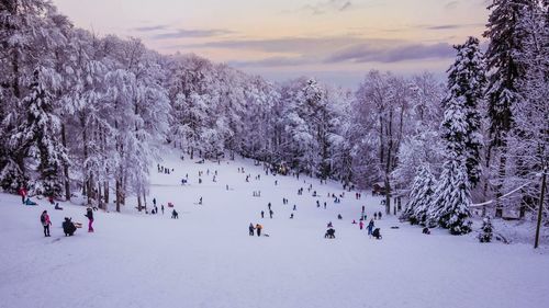 People on snow covered landscape against sky