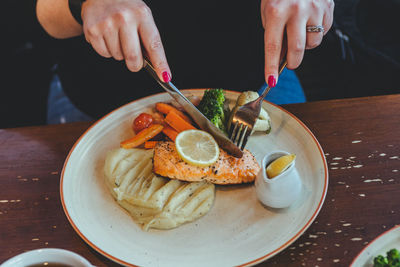 Midsection of woman eating breakfast on table