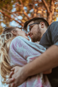 Young couple embracing while standing against trees