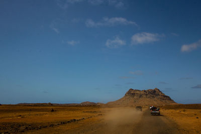 Cars on road amidst land against sky