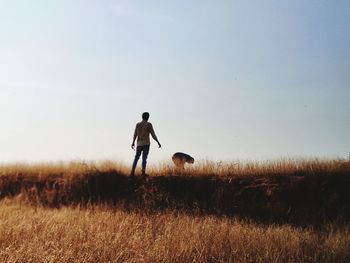 Rear view of man standing on field against sky