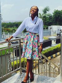 Portrait of young woman standing by railing