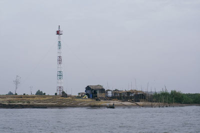 Lighthouse by sea against sky