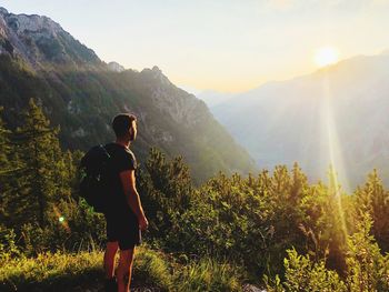 Rear view of woman standing on mountain against sky