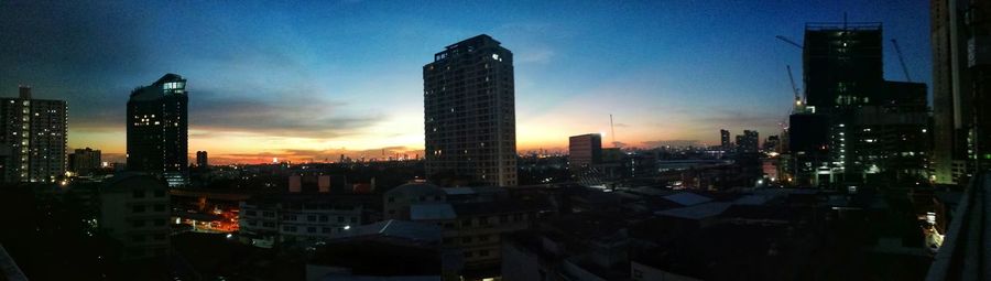 Modern buildings in city against sky at sunset