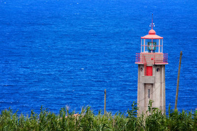 Lighthouse by sea against building