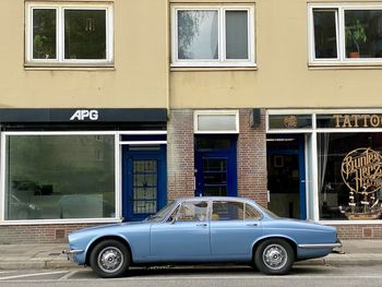 Vintage car on street against buildings in city