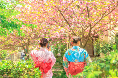 Rear view of friends standing in garden during sunny day