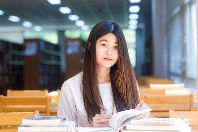 Portrait of beautiful young woman sitting on table