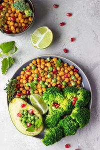 Healthy lunch of broccoli, roasted chickpea, avocado, green peas, pomegranate seeds, lime and mint.