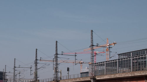 Low angle view of cranes at construction site against sky