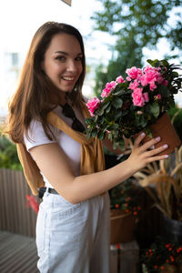Portrait of smiling young woman holding flowers