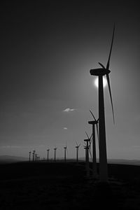 Silhouette windmill on field against sky during sunset