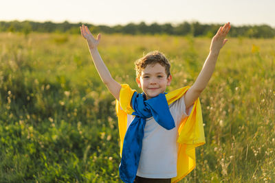 Ukrainian child boy in white t shirt with yellow and blue flag of ukraine in field.