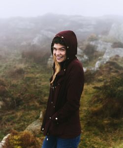 Portrait of smiling young woman standing on landscape against sky