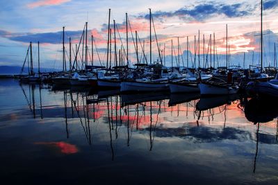 Boats moored in harbor at sunset