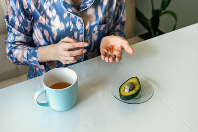 Midsection of woman holding coffee on table