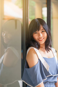 Portrait of smiling woman standing by window