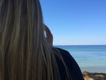 Rear view of woman on beach against clear sky