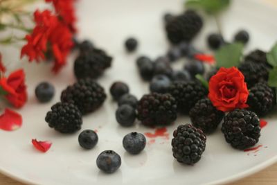 Close-up of berries with red roses on plate