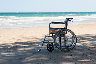 Empty nobody wheelchair on sand of the beach for taking the patient travel