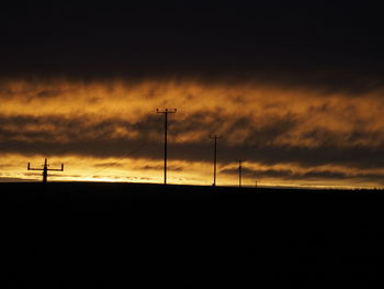 Silhouette landscape against dramatic sky during sunset