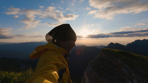 Side view of woman standing on mountain against sky