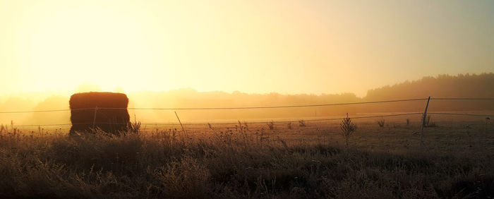 Fence on field against sky during sunset