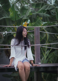 Portrait of young woman sitting on railing