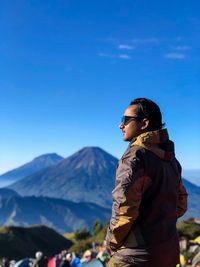 Man standing on mountain against blue sky