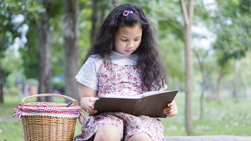 Girl reading book while sitting in park