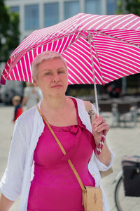 Middle-aged woman with a short haircut with an umbrella protecting from the scorching sun is looking