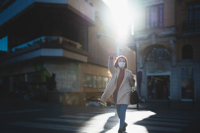 Woman wearing mask walking on street in city