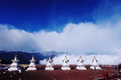 Stupas by snowcapped mountain against sky