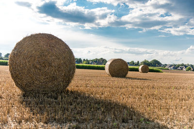 Hay bales on field against sky