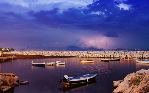 Boats moored at harbor against sky