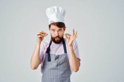 Portrait of chef gesturing against gray background