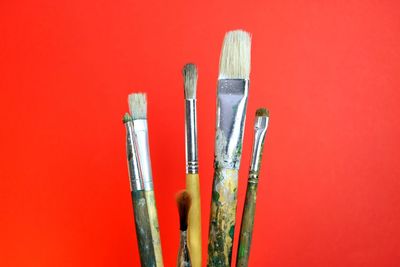 Close-up of paintbrush against red background