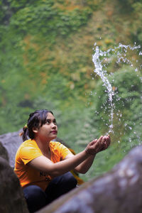 Young woman looking away while splashing water