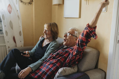 Senior couple sitting on sofa and singing