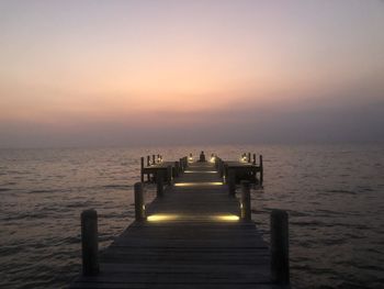 Pier over sea against sky during sunset